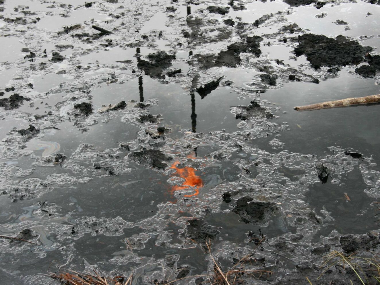 oil slick and pollution with reflection of oil refinery flame